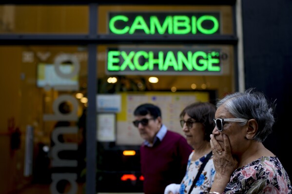 FILE - Pedestrians walk past a money exchange shop in Buenos Aires, Argentina, Oct. 10, 2023. Argentina's new economy minister said in a televised message on Tuesday, Dec. 12, the Argentine peso will be devalued by 50% from 400 to the U.S. dollar to 800 pesos to the dollar (AP Photo/Natacha Pisarenko, File)