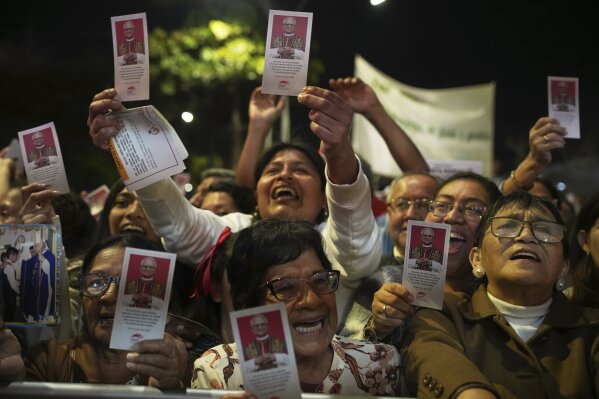 People celebrate waving flyers of newly-elected Pope Leo XIV during a Mass in his honor, in Chiclayo, Peru, Saturday, May 10, 2025. (AP Photo/Guadalupe Pardo)