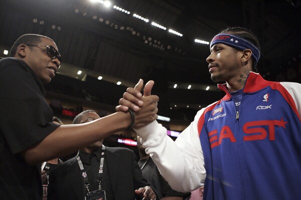 FILE - Rapper Jay-Z, left, shakes hands with NBA All-Star Philadelphia 76ers' Allen Iverson before the start of the NBA All-Star basketball game in Houston, Feb. 19, 2006. Just as a movie soundtrack helps viewers follow the action of the narrative through each plot twist, hip-hop has done the same for basketball via the NBA. A legacy was passed to Iverson when he entered the NBA in 1996, embodying hip-hop culture in everything he did, from his clothes to his corn rows. (AP Photo/LM Otero, file)