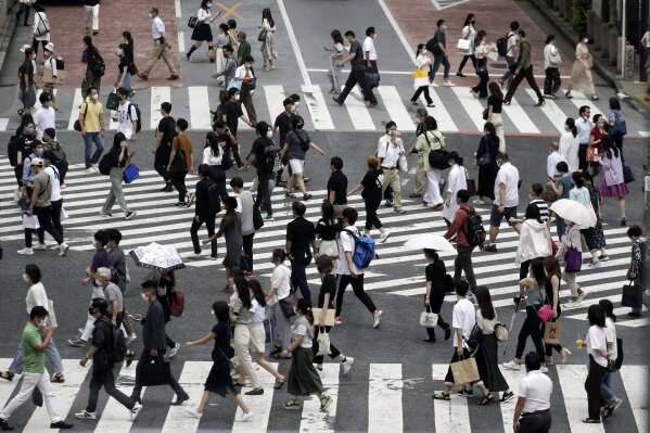 FILE - In this July 31, 2020, file photo, people wearing face masks against the spread of the coronavirus walk at Shibuya pedestrian crossings in Tokyo. Japan’s exports plunged 19.2% in July from a year earlier, as the coronavirus pandemic sapped global demand for goods from the third largest economy, government data showed Wednesday, Aug. 19, 2020. (AP Photo/Eugene Hoshiko, File)