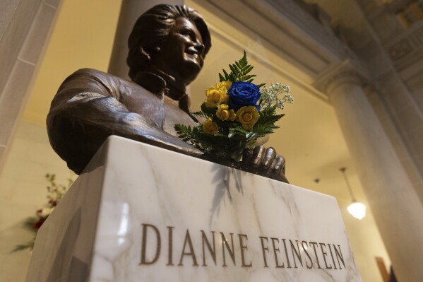 FILE - Flowers rest at a bust depicting U.S. Sen. Dianne Feinstein at City Hall in San Francisco on Sept. 29, 2023. The body of the late senator will lie in state Wednesday, Oct. 4, at San Francisco's City Hall for mourners wishing to say goodbye to their 'forever mayor.' It is the building where Feinstein served as supervisor and the city's first female mayor before departing for a groundbreaking career in Congress three decades ago. (AP Photo/ Benjamin Fanjoy, File)