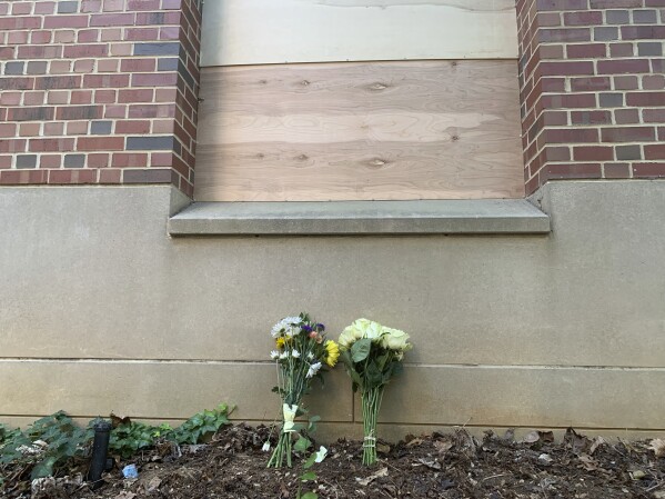Flores yacían debajo de una ventana tapiada en Caudill Labs en el campus de UNC-Chapel Hill en Chapel Hill, Carolina del Norte, el martes 29 de agosto de 2023, después de que un estudiante graduado matara a tiros a su asesor docente. El martes se pudo ver un agujero de bala en la esquina inferior izquierda de esa ventana. (Foto AP/Hannah Schoenbaum)