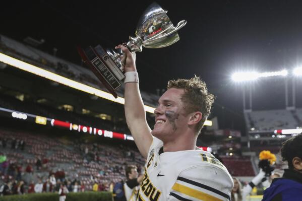 Missouri quarterback Brady Cook hoists the Mayor's Cup after winning an NCAA college football game against South Carolina, Saturday, Oct. 29, 2022, in Columbia, S.C. (AP Photo/Artie Walker Jr.)