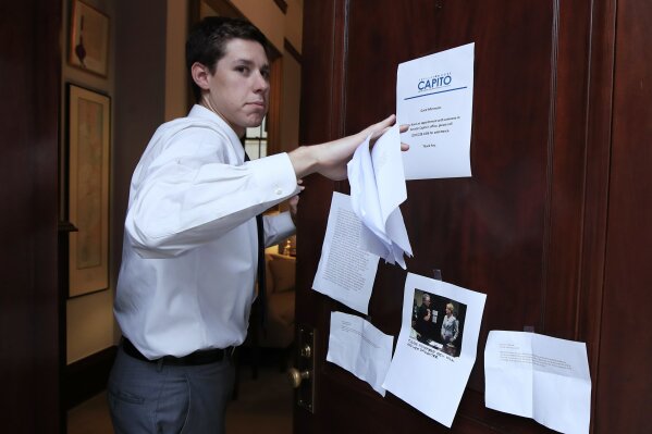 
              A staffer for Sen. Shelley Moore Capito, R-W.Va. takes down leaflets left by a group of protestors at her Russell Senate Office Building office on Capitol Hill in Washington, Tuesday, July 18, 2017. (AP Photo/Manuel Balce Ceneta)
            