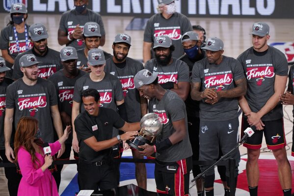 Miami Heat head coach Erik Spoelstra, center left, hands the Eastern Conference trophy to Bam Adebayo (13) as they celebrate their NBA conference final playoff basketball game win over the Boston Celtics with the Eastern Final trophy Sunday, Sept. 27, 2020, in Lake Buena Vista, Fla. (AP Photo/Mark J. Terrill)