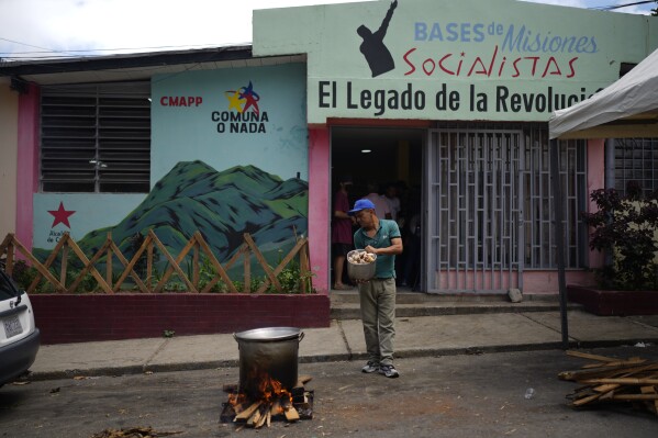 A man holds a bucket of meat as he prepares a soup outside of a building affiliated with the ruling United Socialist Party of Venezuela during a test voter organizing campaign ahead of upcoming presidential elections in Caracas, Venezuela, Sunday, June 9, 2024. (AP Photo/Ariana Cubillos)