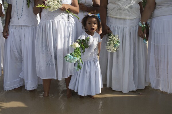 A child sings while holding flowers as offering for the African goddess of the sea, Yemanja, during her annual celebration, on Arpoador Beach in Rio de Janeiro, Sunday, Feb. 2, 2025. (AP Photo/Bruna Prado)
