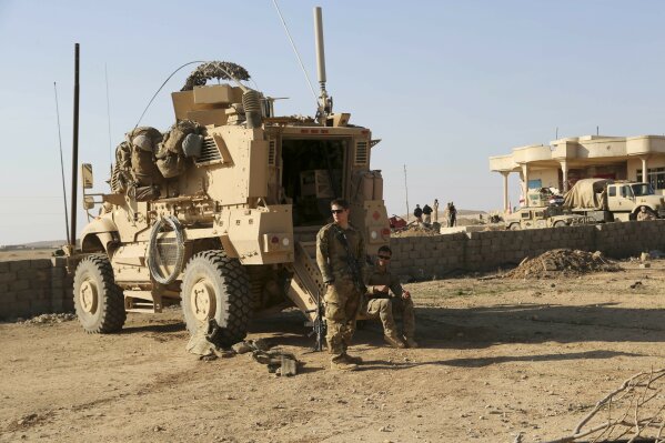 FILE - In this Feb. 23, 2017 file photo, U.S. Army soldiers stand outside their armored vehicle on a joint base with the Iraqi army, south of Mosul, Iraq. In a quest to root out Islamic State group hideouts over the summer, Iraqi forces on the ground cleared nearly 90 villages across a notoriously unruly northern province. But the much-touted operation still relied heavily on U.S. intelligence, coalition flights and planning assistance. (AP Photo/ Khalid Mohammed, File)