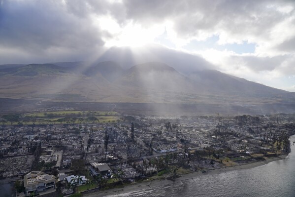 FILE - Rays of sunlight pierce through the clouds, Thursday, Aug. 10, 2023, above homes burned by wildfires in Lahaina, Hawaii. (AP Photo/Rick Bowmer, File)