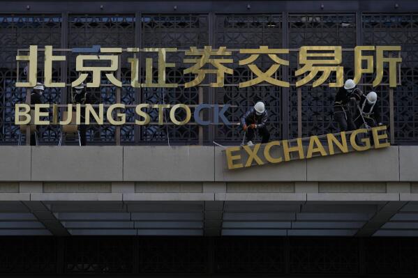 FILE - Workers install the nameplate of the Beijing Stock Exchange on the Financial Street in Beijing, Nov. 14, 2021. China on Thursday, Feb. 17, 2022, rejected a U.S. accusation that Beijing is failing to live up to its market-opening commitments in a new round of complaints as companies wait for the two governments to restart talks on ending a tariff war. (AP Photo/Andy Wong, File)