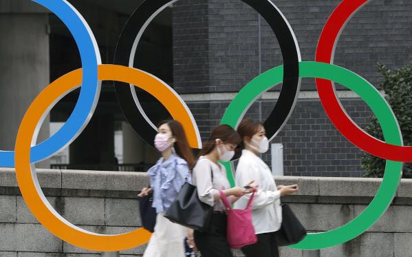 People wearing face masks walk past the Olympics Rings statue in Tokyo, Thursday, July 8, 2021. Japan is set to place Tokyo under a state of emergency starting next week and lasting through the Olympics, with COVID-19 cases surging and feared to multiply during the Games. (Shinji Kita/Kyodo News via AP)