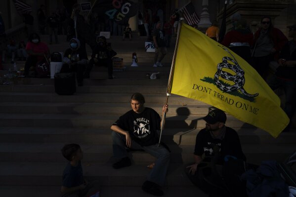 FILE - In this Nov. 8, 2020, file photo, a Donald Trump who would only give her first name, Dianna, sits on the steps of the State Capitol with her family as a protest against the presidential election results winds down in Lansing, Mich. While the state has swung back to Democrats since Trump's narrow 2016 win, choosing President Joe Biden by more than 150,000 votes, Michigan's Republican Party has taken a hard right turn.
Its own Capitol in Lansing was the rallying point in April for armed Michigan Liberty Militia protesting pandemic restrictions, including some members who were later charged with plotting to kidnap Democratic Gov. Gretchen Whitmer. (AP Photo/David Goldman, File)