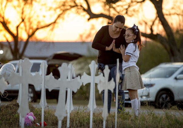 
              Meredith Cooper, of San Antonio, Texas, and her 8-year-old daughter, Heather, visit a memorial of 26 metal crosses near First Baptist Church in Sutherland Springs, Texas, Monday Nov. 6, 2017. The gunman of a deadly shooting at the small-town Texas church had a history of domestic violence and sent threatening text messages to his mother-in-law, a member of First Baptist, before the attack, authorities said Monday. (Jay Janner/Austin American-Statesman via AP)
            