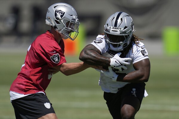 Las Vegas Raiders' quarterback Cam Miller hands off a ball to Ashton Jeanty during an NFL football rookie mini camp Friday, May 9, 2025, in Henderson, Nev. (AP Photo/John Locher)
