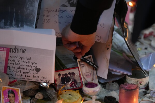 Geoff Payne, the father of former One Direction singer Liam Payne, touches a gel bracelet hanging on a picture of his son while visiting a memorial outside the Casa Sur Hotel where the British pop singer fell to his death from a hotel balcony, in Buenos Aires, Argentina, Friday, Oct. 18, 2024. (AP Photo/Natacha Pisarenko)