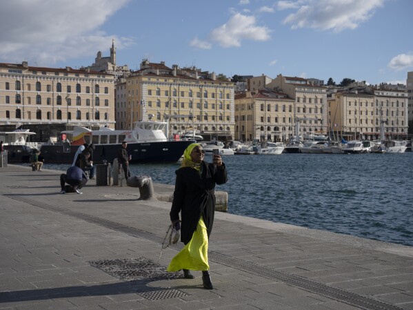 A woman walks along the Vieux Port in Marseille, southern France, Monday, April 22, 2024. (AP Photo/Daniel Cole)