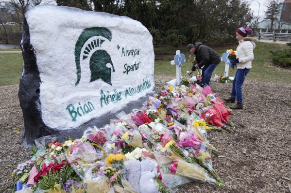 FILE - Mourners leave flowers at The Rock on the grounds of Michigan State University following a shooting in East Lansing, Mich., Wednesday, Feb. 15, 2023. Alexandria Verner, Brian Fraser and Arielle Anderson were killed and several other students wounded after a gunman opened fire on the campus of Michigan State University. The school board approved settlements with the victims' families, Friday, Dec. 15, 2023. (AP Photo/Paul Sancya, File)