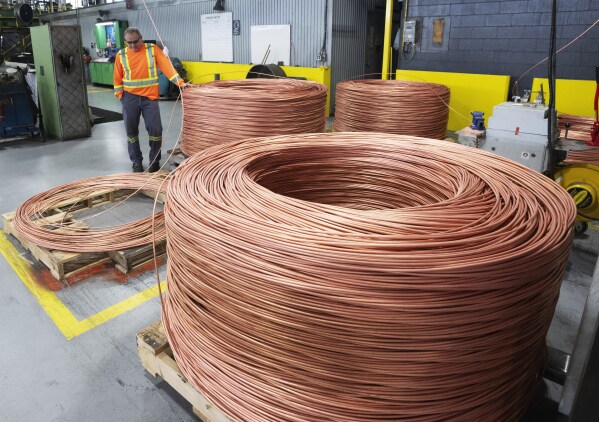 Ein Arbeiter betrachtet am Freitag, 12. April 2024, in der Nähe von Montreal eine Spule bei Nexans, einem der weltweit größten Draht- und Kabelhersteller.  Das Unternehmen mischt seinen Produkten zunehmend Altkupfer bei.  (Ryan Remiorz/The Canadian Press über AP)