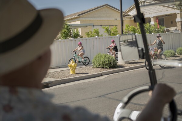 Residents greet Joe Johnston, founder of Agritopia, a community nestled around a plot of agricultural land, as he makes his rounds in his golf cart April 22, 2025, in Gilbert, Ariz. (AP Photo/Annika Hammerschlag)