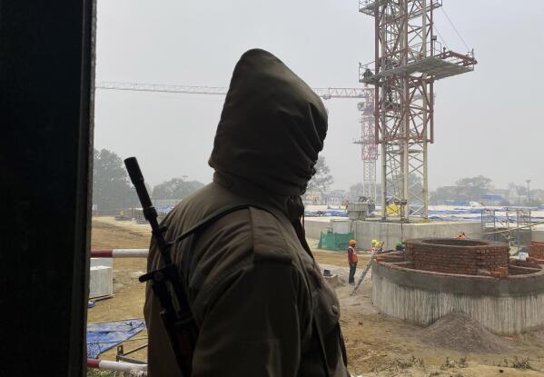 A security man stands guard as laborers build a Hindu temple dedicated to Hindu god, Ram, demanded by millions of Hindus for over 100 years in Ayodhya, in the Indian state of Uttar Pradesh, Feb. 3, 2022. It's one of several frenetic constructions underway in Ayodhya, where Prime Minister Narendra Modi's Bharatiya Janata Party is seeking reelection by touting Hindu-first politics coupled with economic prosperity. Over 150 million people are expected to vote in the state across seven phases starting Thursday before results are declared in March. (AP Photo/Rajesh Kumar Singh)