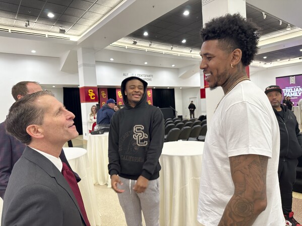 Eric Musselman, left, talks with current player Isaiah Collier, center and former player Nick Young after his introduction as the new head coach for Southern California's NCAA college basketball team, Friday, April 5, 2024, in Los Angeles. (AP Photo/Beth Harris)