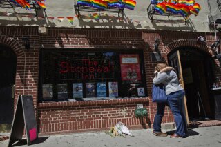 FILE- In this June 12, 2016 file photo, a couple embraces outside the Stonewall Inn in New York. On Thursday, June 6, 2019, Commissioner James O'Neill apologized for the 1969 police raid at the Stonewall Inn, which catalyzed the modern LGBT rights movement. O'Neill said Thursday that "the actions taken by the NYPD were wrong" at the gay bar in New York City's Greenwich Village. He called the actions and laws of the time discriminatory and said, "For that, I apologize." (AP Photo/Mary Altaffer, File)
