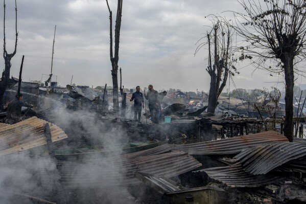 Kashmiris look at the debris after a fire gutted several houseboats early morning in the interiors of Dal Lake, on the outskirts of Srinagar, Indian controlled Kashmir, Saturday, Nov. 11, 2023. A massive fire engulfed some wooden houseboats on Saturday and three charred bodies were recovered from the wreckage, officials said. (AP Photo/Dar Yasin)
