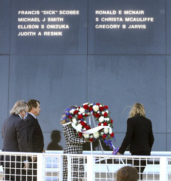 The sun illuminates the seven names of the astronauts killed in the 1986 Challenger shuttle disaster as a wreath is laid at the base of the Space Mirror Memorial during a 35th anniversary commemoration ceremony at Kennedy Space Center, Fla., Thursday, January 28, 2021. (Joe Burbank/Orlando Sentinel via AP)
