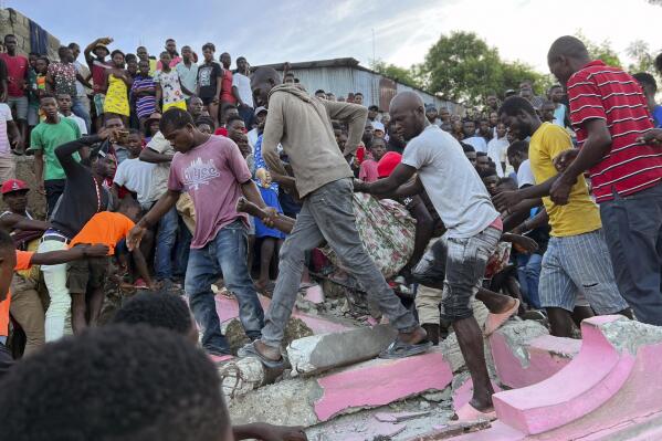 People carry an injured person away from a home that collapsed due to an earthquake in Jeremie, Haiti, Tuesday, June 6, 2023. (AP Photo/Ralph Simon)