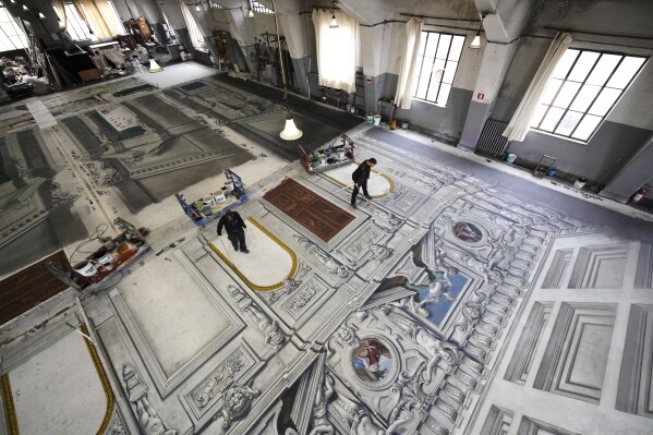 Set designers work on a stage canvas in the "Teatro dell' Opera" opera house warehouse, in Rome, Thursday, April 10, 2025. (AP Photo/Andrew Medichini)
