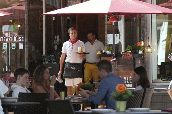 A waiter carries drinks, Friday, April 18, 2025, in Miami Beach, Fla. (AP Photo/Marta Lavandier, File)