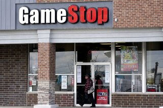 A woman wears a face mask as she walks past a GameStop store in Des Plaines, Ill., Thursday, Oct. 15, 2020. The latest battleground between the proletariat and the hedge funds serving the 1% isn’t on just any street. It’s on Wall Street. At least, that’s the view within an army of smaller-pocketed, optimistic investors who are throwing dollars and buy orders at the stock of video-game retailer GameStop. (AP Photo/Nam Y. Huh, file)