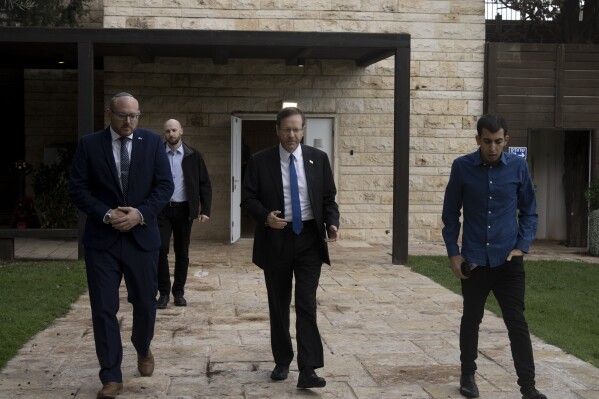Israel's President Isaac Herzog, center, walks with his staff after an interview at his official residence in Jerusalem, Thursday, Dec. 14, 2023. (AP Photo/Maya Alleruzzo)