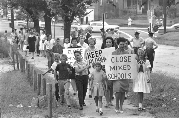 FILE - Mothers carrying protest signs accompany their children to Graymont Elementary School in Birmingham, Ala., which was opened on an integrated basis, Sept. 4, 1963. Friday, May 17, 2024, marks 70 years since the U.S. Supreme Court ruled that separating children in schools by race was unconstitutional. On paper, Brown v. Board of Education still stands. In reality, school integration is all but gone, the victim of a gradual series of court cases that slowly eroded it, leaving little behind. (AP Photo, File)