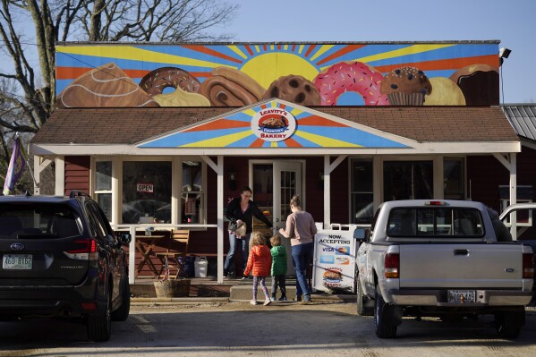 A customer holds the door for a family arriving at Leavitt's Country Bakery, Thursday, April 13, 2023, in Conway, N.H. Lawyers in a First Amendment lawsuit that pits a New Hampshire bakery owner against a town zoning ordinance over a large painting of doughnuts and other pastries are hoping that a judge can resolve the matter after voters didn't. (AP Photo/Robert F. Bukaty, File)