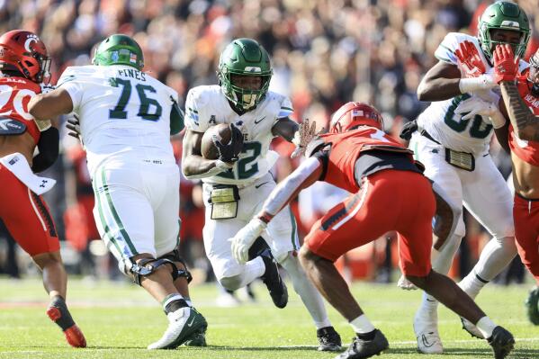 Tulane running back Tyjae Spears (22) carries the ball for a touchdown as he stiff-arms Cincinnati safety Ja'von Hicks (3) during the first half of an NCAA college football game, Friday, Nov. 25, 2022, in Cincinnati. (AP Photo/Aaron Doster)