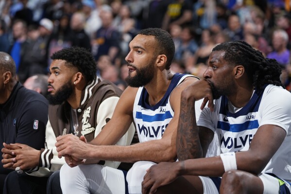 Minnesota Timberwolves centers Karl-Anthony Towns, Rudy Gobert and Naz Reid, from left, watch from the bench late in the second half of the team's NBA basketball game against the Denver Nuggets on Wednesday, April 10, 2024, in Denver. (AP Photo/David Zalubowski)