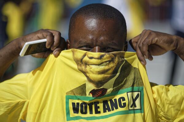 FILE - A supporter of the ruling African National Congress (ANC) holds up a T-shirt of President Cyril Ramaphosa as he attends their final election rally at Ellis Park stadium in Johannesburg, South Africa,  May 5, 2019. South African President Cyril Ramaphosa is challenged Wednesday Jan. 5, 2022 to take decisive action against the corruption documented in a judicial report presented to the leader and made public. The report recommends criminal prosecution against several high-profile officials often taking orders from former President Jacob Zuma during his presidency from 2009 to 2018.(AP Photo/Ben Curtis, File)
