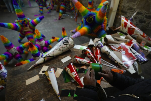Un fabricante de piñatas trabaja en un diseño tradicional, una esfera y siete púas, en un negocio familiar de fabricación de piñatas en Acolman, justo al norte de la Ciudad de México, el miércoles 13 de diciembre de 2023. Este estilo de piñata tiene un origen religioso. Cada cono representa uno de los siete pecados capitales, y golpear el globo con un palo es un golpe simbólico contra el pecado.  (Foto AP/Fernando Llano)