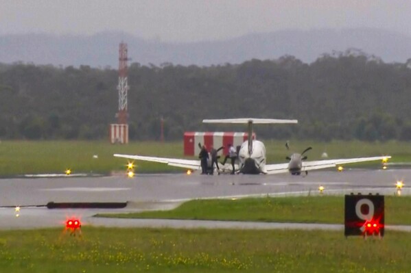 In this image taken from video, passengers alight after a light plane with three people aboard landed safely without landing gear at Newcastle Airport, Australia, Monday, May 13, 2024, after circling the airport for almost three hours to burn off fuel. The twin-turboprop Beechcraft Super King Air had just taken off from the airport north of Sydney for a 180-kilometer (112-mile) flight north to Port Macquarie when the pilot raised the alarm saying the landing gear had failed. (Channel 10 via AP)