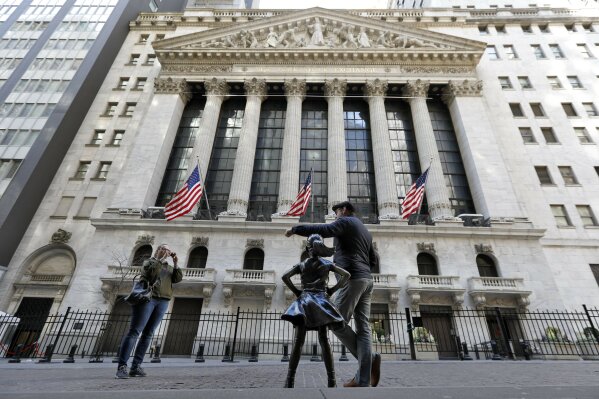 A man poses for a photo with the Fearless Girl statue in front of the New York Stock Exchange, Sunday, March 15, 2020. New York Gov. Andrew Cuomo Cuomo said Saturday that more than 600 New Yorkers have been diagnosed with COVID-19, the disease caused by the virus. (AP Photo/Richard Drew)