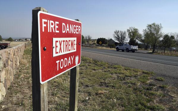 A fire warning sign is pictured in Las Vegas, N.M., on Tuesday, May 3, 2022. Flames raced across more of New Mexico's pine-covered mountainsides, Tuesday, May 3, 2030, charring more than 217 square miles over the last several weeks. (AP Photo/Thomas Peipert)