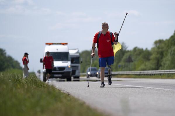 Oleksandr Shvetsov, Ukrainian war veteran, walks along a highway towards Kyiv from Zhytomyr to meet his friend Serhii Khrapko ahead of their 120-kilometer (75 mile) walk to raise money for medical equipment in honor of their comrades wounded in Russia's war against their homeland in Stavyshche, Zhytomyr region, Ukraine, on Thursday, May 18, 2023. They raised 3.1 million hryvnias ($84,000), short just the 500,000 hryvnias ($14,000) needed to purchase a new gastroscope for Ukraine's National Military Medical Clinical Center. (AP Photo/Roman Hrytsyna)