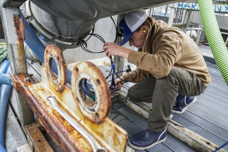 Lane Bolich, captain of the Harmony, reattaches a new hose for the boat’s tendering tanks, Saturday, June 24, 2023, in Kodiak, Alaska. (AP Photo/Joshua A. Bickel)