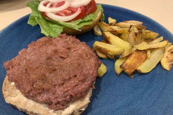A Beyond Burger, made with lettuce, tomato and onion, is plated with a side of potato fries at a home in Westchester County, N.Y. on Jan. 10, 2022. Plant-based meat products aim to imitate meat in taste, texture, appearance and smell, and the likenesses are now pretty impressive. They can also be used in pasta sauces, stir fries and casseroles. (AP Photo/Julia Rubin)