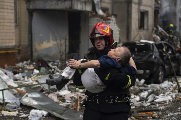 A firefighter carries a man from a damaged residential building after a Russian missile strike, in Kyiv, Ukraine, Tuesday, Jan. 2, 2024. (AP Photo/Alex Babenko)