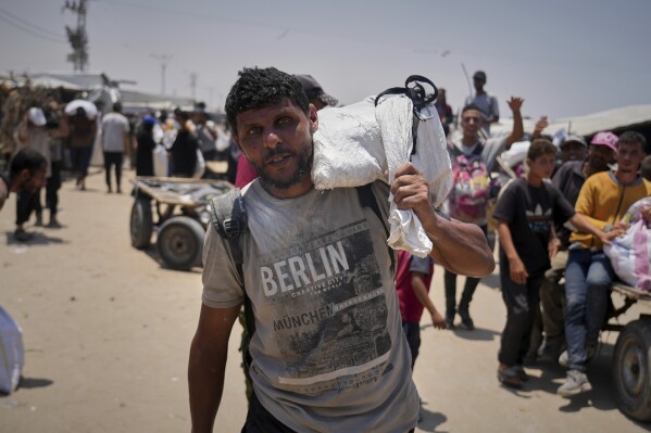 Omar al-Hobi, 43, from Rafah, carries a bag of food he collected at a distribution center run by private contractor the Gaza Humanitarian Foundation in the southern Gaza Strip, as he arrives at his tent in Khan Younis, Tuesday, June 10, 2025. (AP Photo/Abdel Kareem Hana)