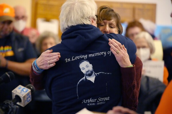 CAPTION CORRECTION CORRECTS NAME AND DATE: Arthur Barnard, the father of Lewiston, Maine mass shooting victim Arthur Strout, is hugged after speaking at an anti-gun demonstration at the State House, Wednesday, Jan. 3, 2024, in Augusta, Maine. (AP Photo/Robert F. Bukaty)