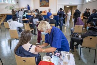 FILE - A student at Holtet high school receives the first dose of Pfizer vaccine against COVID-19 in the school's auditorium in Oslo, Sept. 7, 2021. Authorities in Norway said on Thursday, Dec. 2 at least 50 people in Oslo have been infected with the omicron coronavirus variant. The Norwegian Institute of Public Health said the cases are connected to a company’s Christmas party in a restaurant in the capital. (Heiko Junge/NTB via AP, file)
