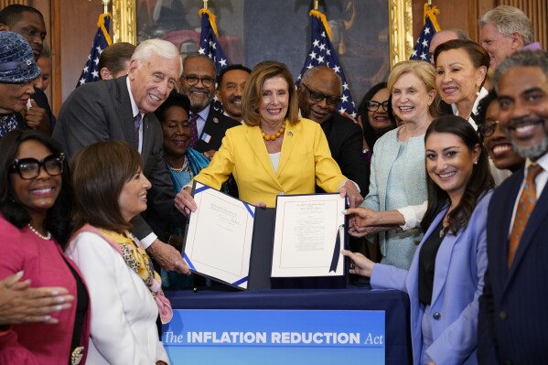 FILE - House Speaker Nancy Pelosi of Calif., and the House Democrats with her, celebrate after Pelosi signed the Inflation Reduction Act of 2022 during a bill enrollment ceremony on Capitol Hill in Washington, Aug. 12, 2022. It's a once-in-a-generation undertaking, thanks to three big bills approved by Congress last session. They're now coming online. President Joe Biden calls it "Bidenomics." Republicans criticize it as big government overreach. Taken together, the estimated $2 trillion is a centerpiece of Biden's re-election effort. (AP Photo/Susan Walsh, File)